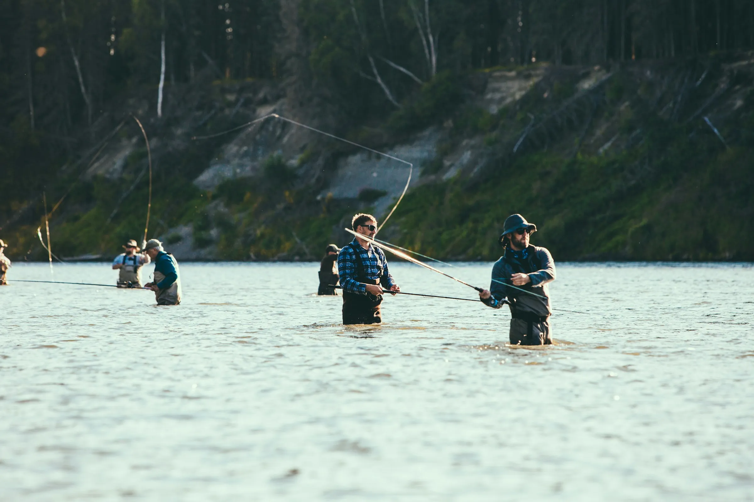 Anglers wading a glacial turquoise river on the Kenai Peninsula, rods bent