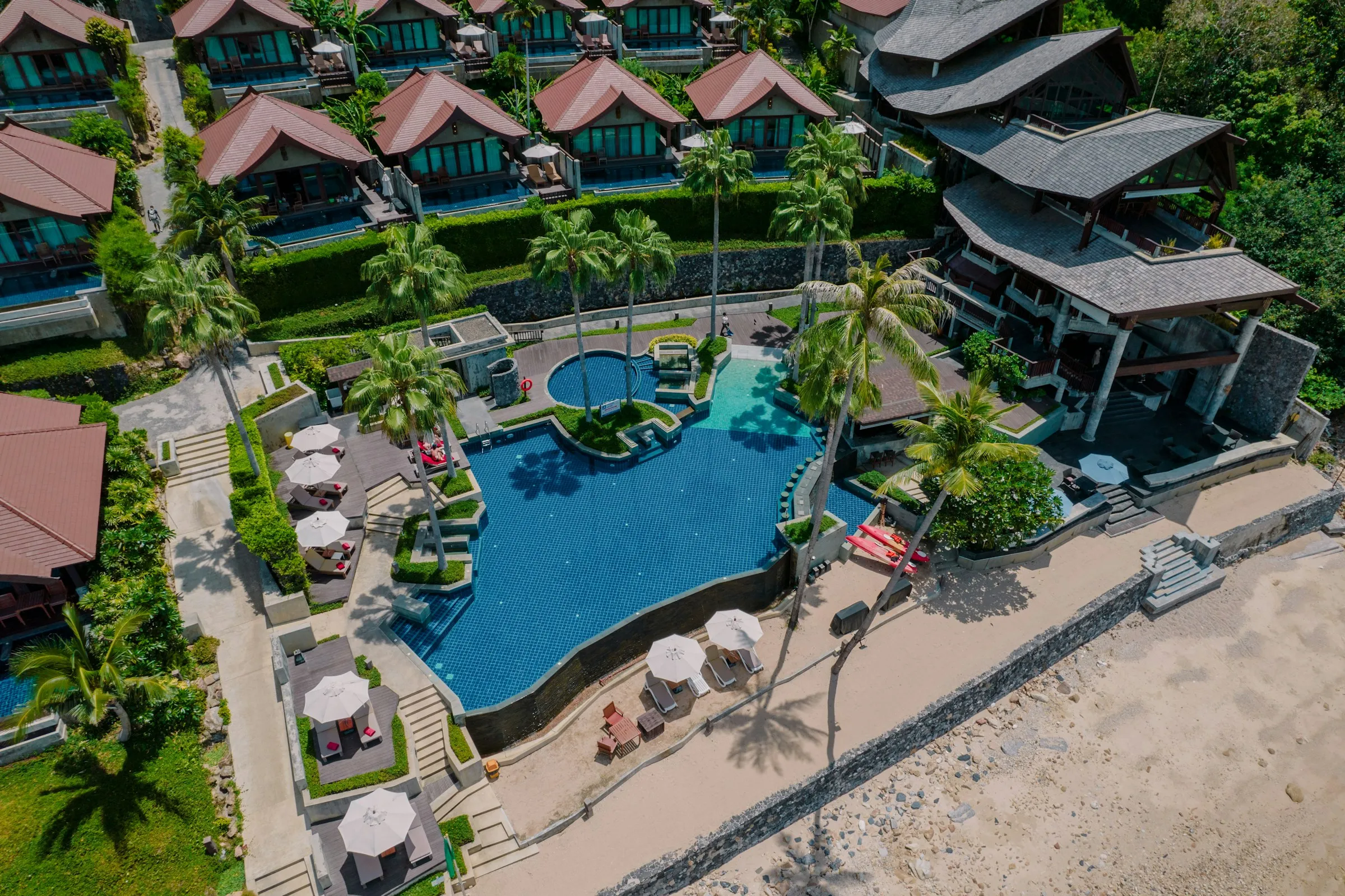 Aerial view of a beach resort pool and villas