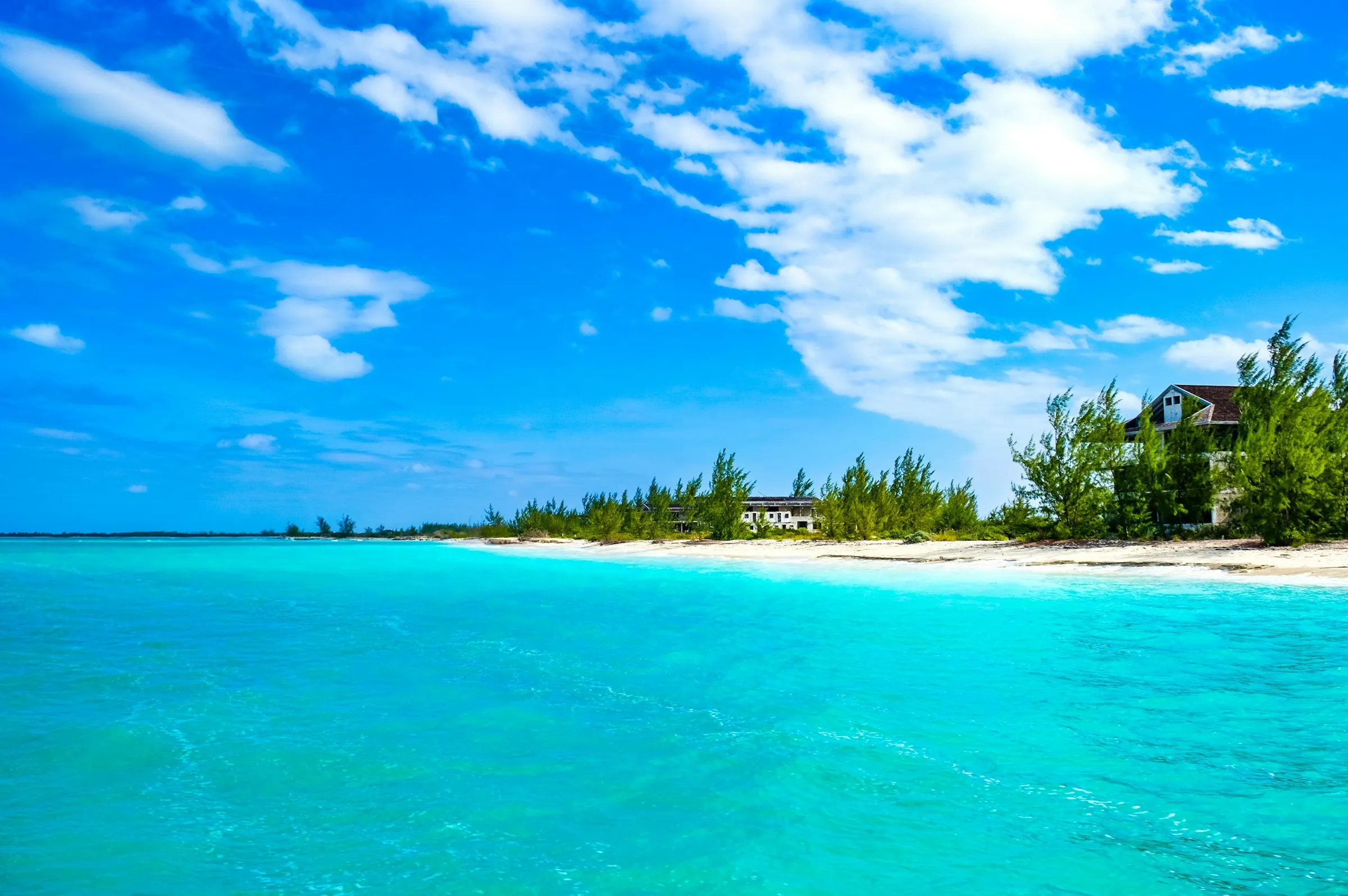 A low island of white sand and palms surrounded by Turks and Caicos turquoise