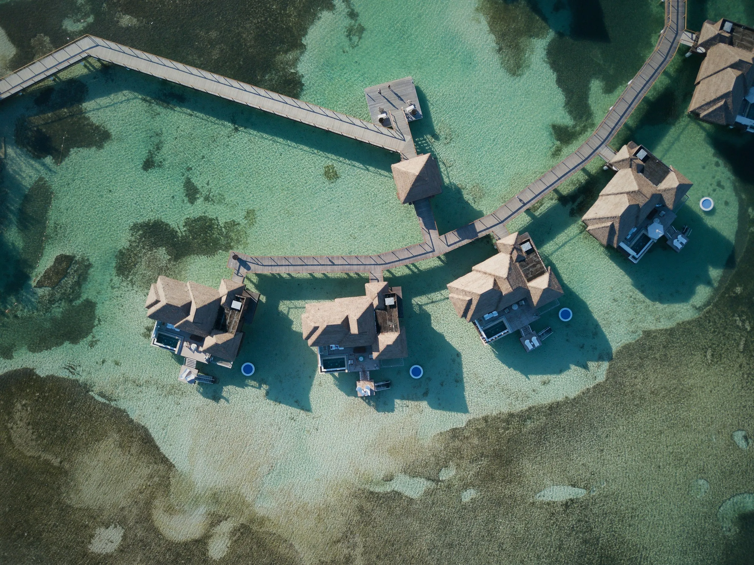 Overwater bungalows on a turquoise lagoon from above