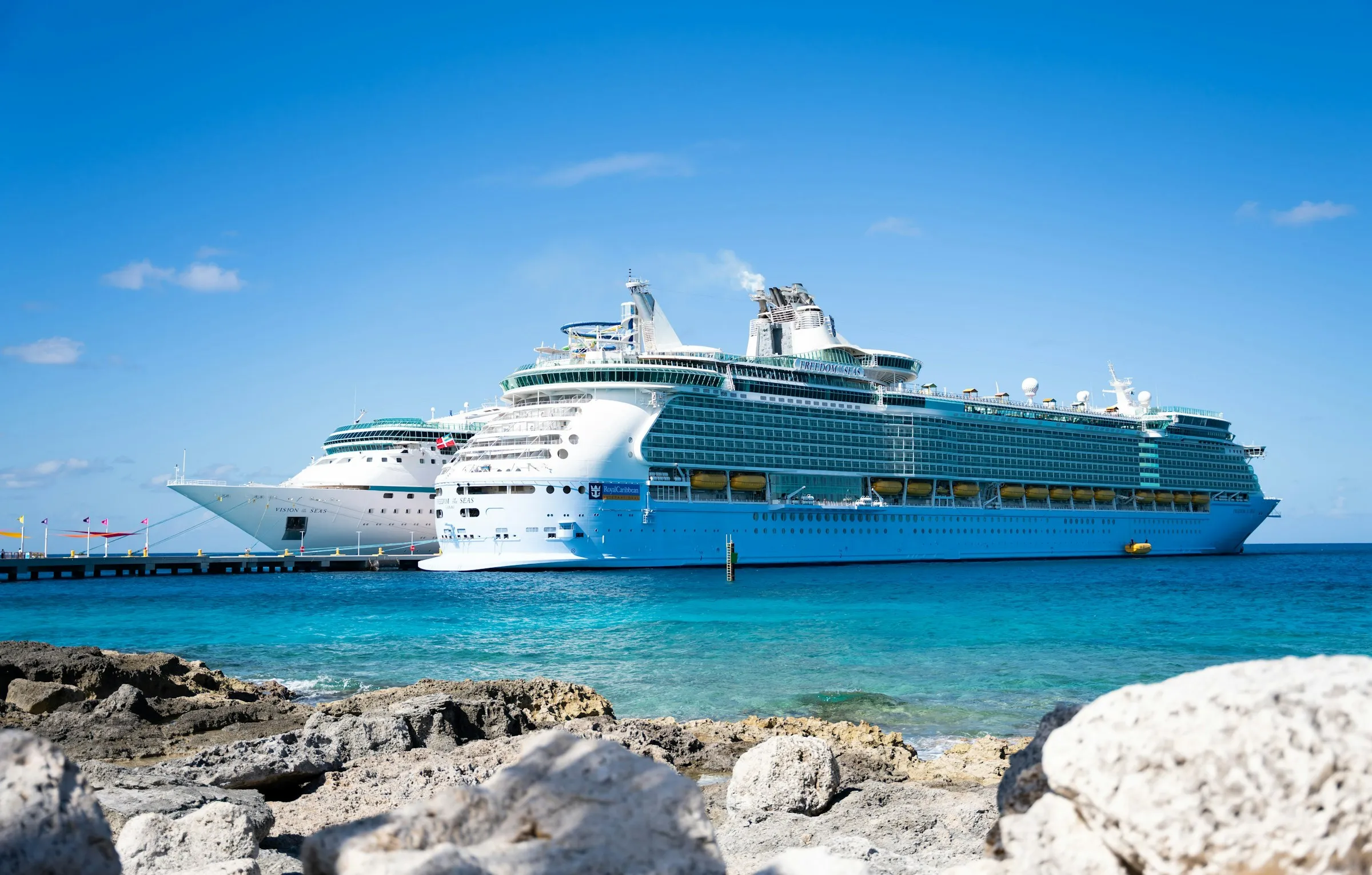 A cruise ship anchored off a rocky Caribbean beach