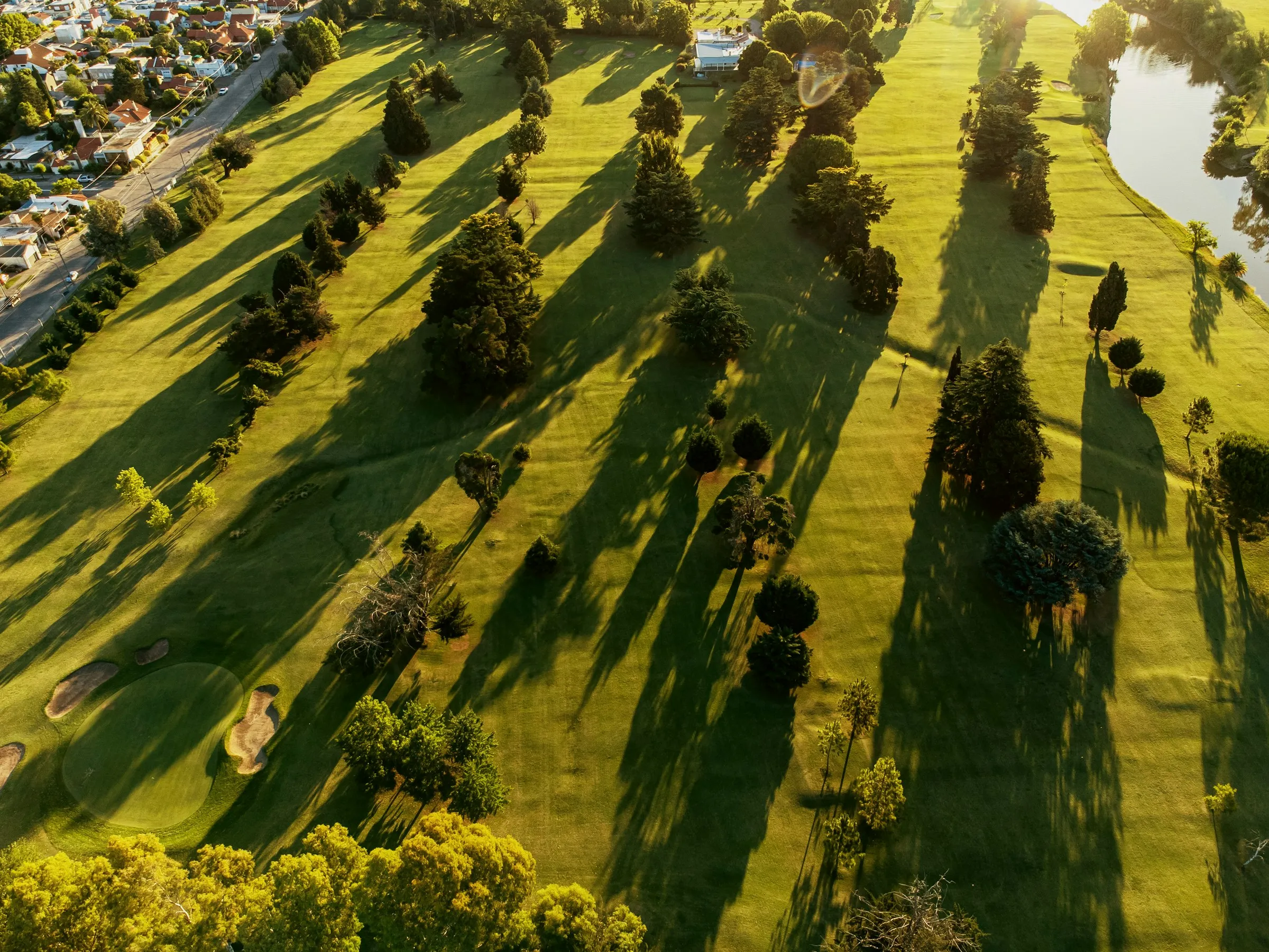 Aerial view of a tree-lined golf course at golden hour