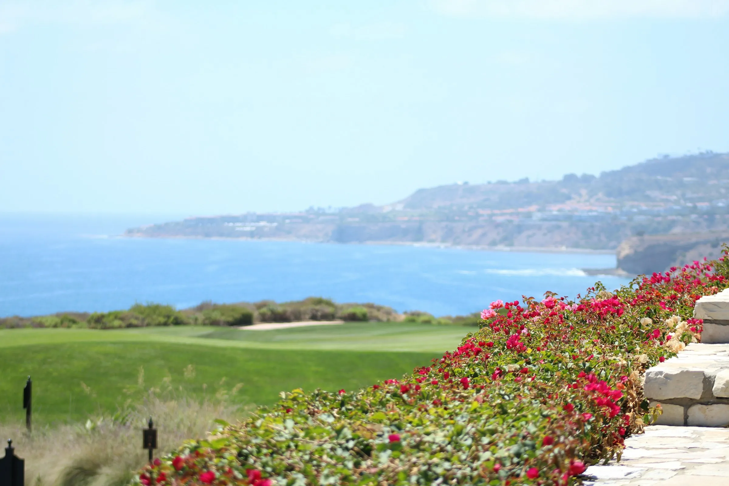 A flower-lined golf hole overlooking the sea