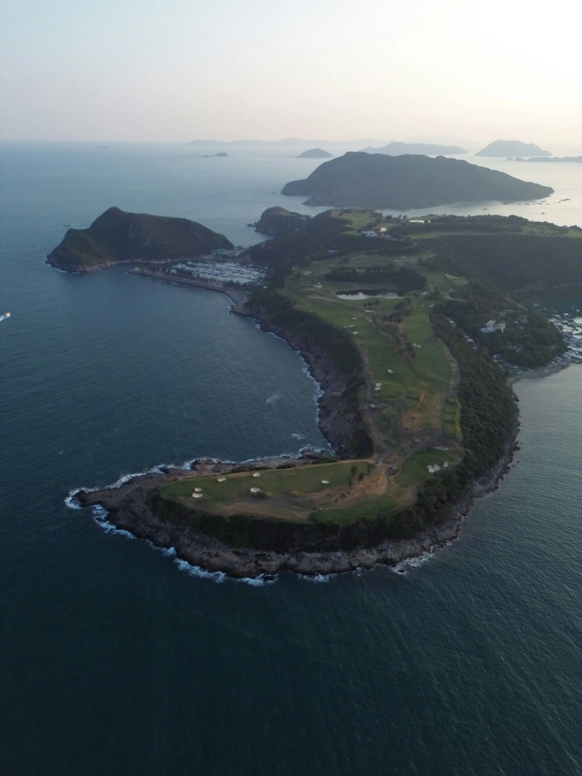 Aerial view of a golf course on a green peninsula in the sea