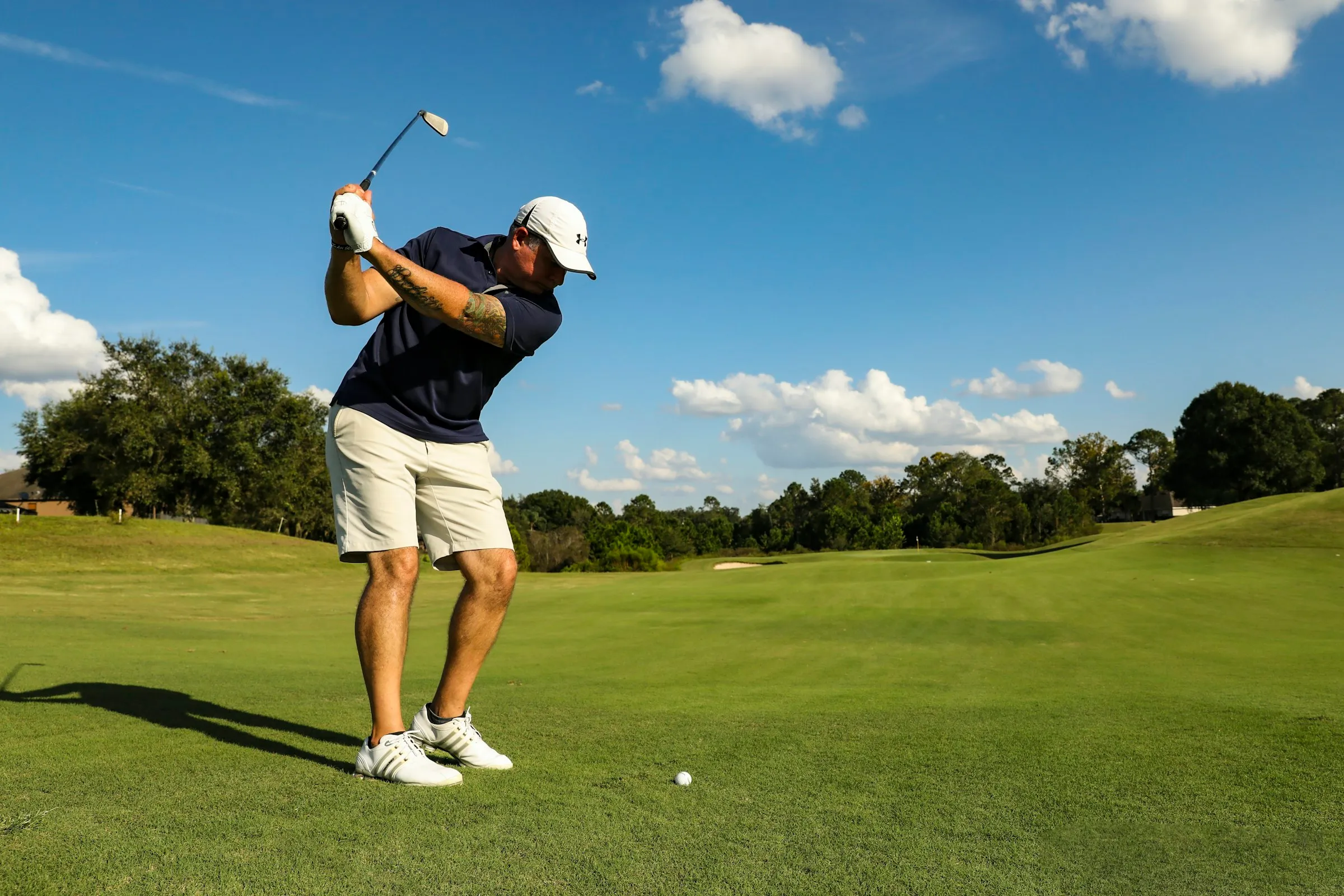 A golfer mid-swing on a sunny fairway
