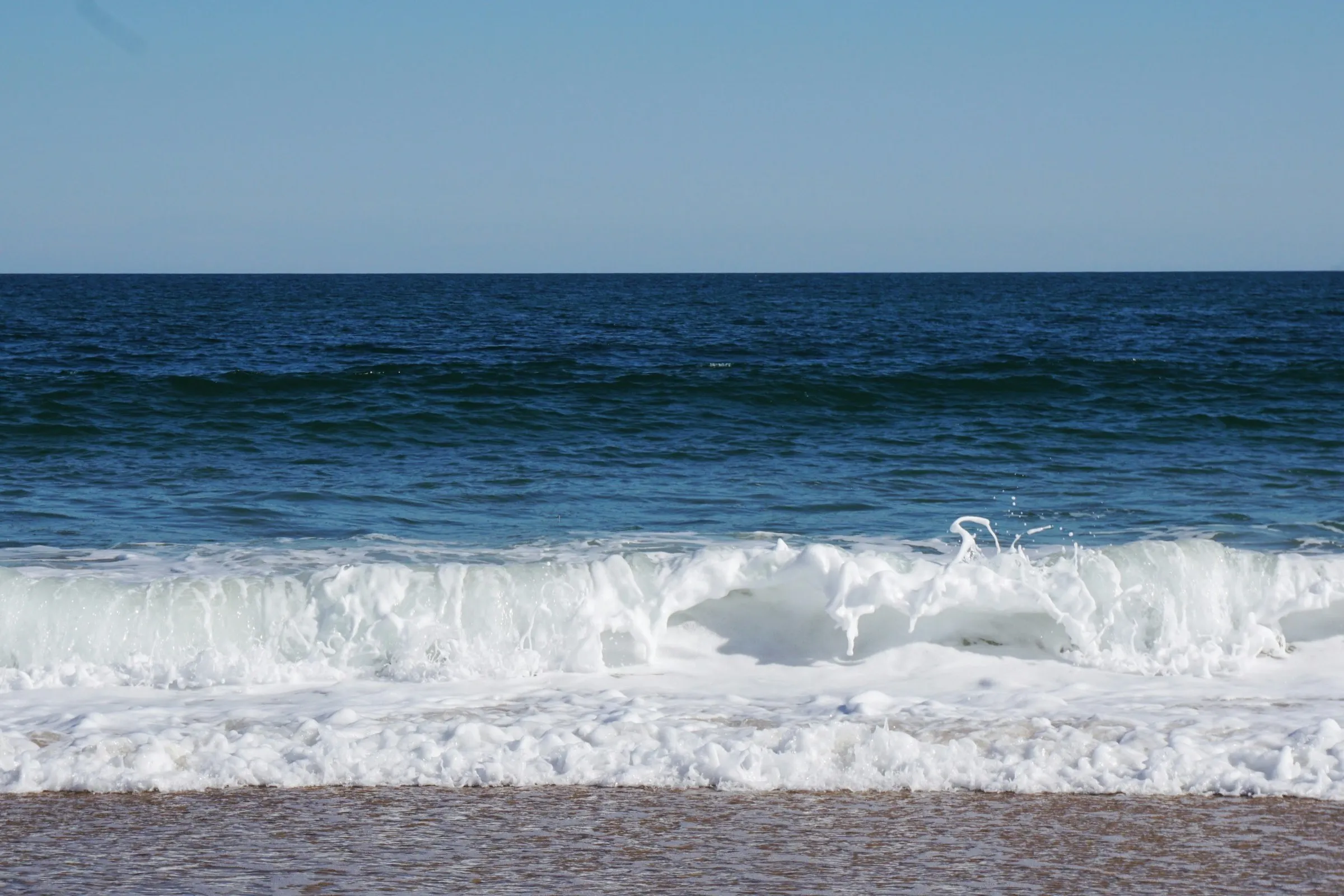 A wave breaking on a wide Hamptons beach