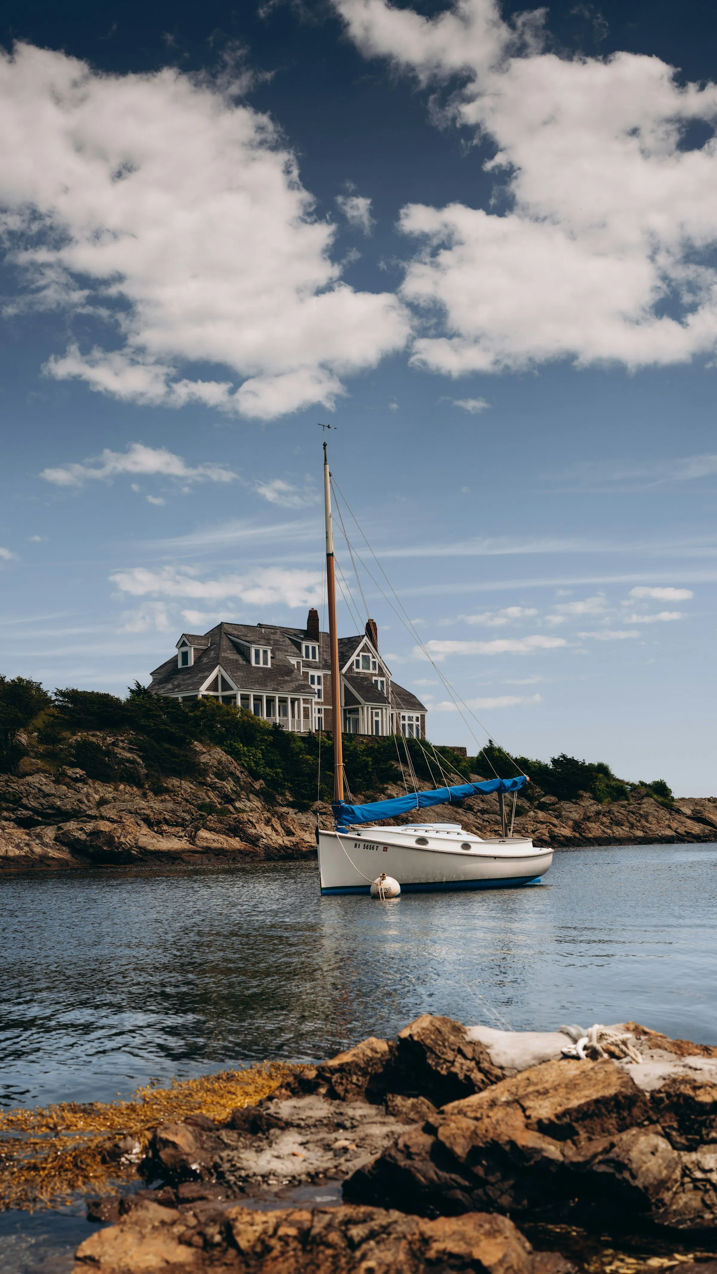 A shingled house and sailboat on the Newport, Rhode Island shore